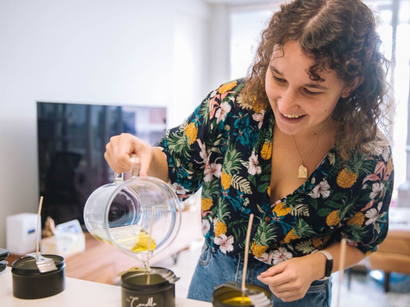 woman smiling and pouring candle wax 